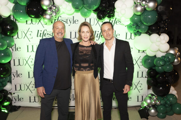 Three people dressed in semi-formal attire pose together, smiling, in front of a "LUXE" and "lifestyle" backdrop with green, white, and black balloons at the 2025 Women of Influence and Men of Influence event. Lifestyle